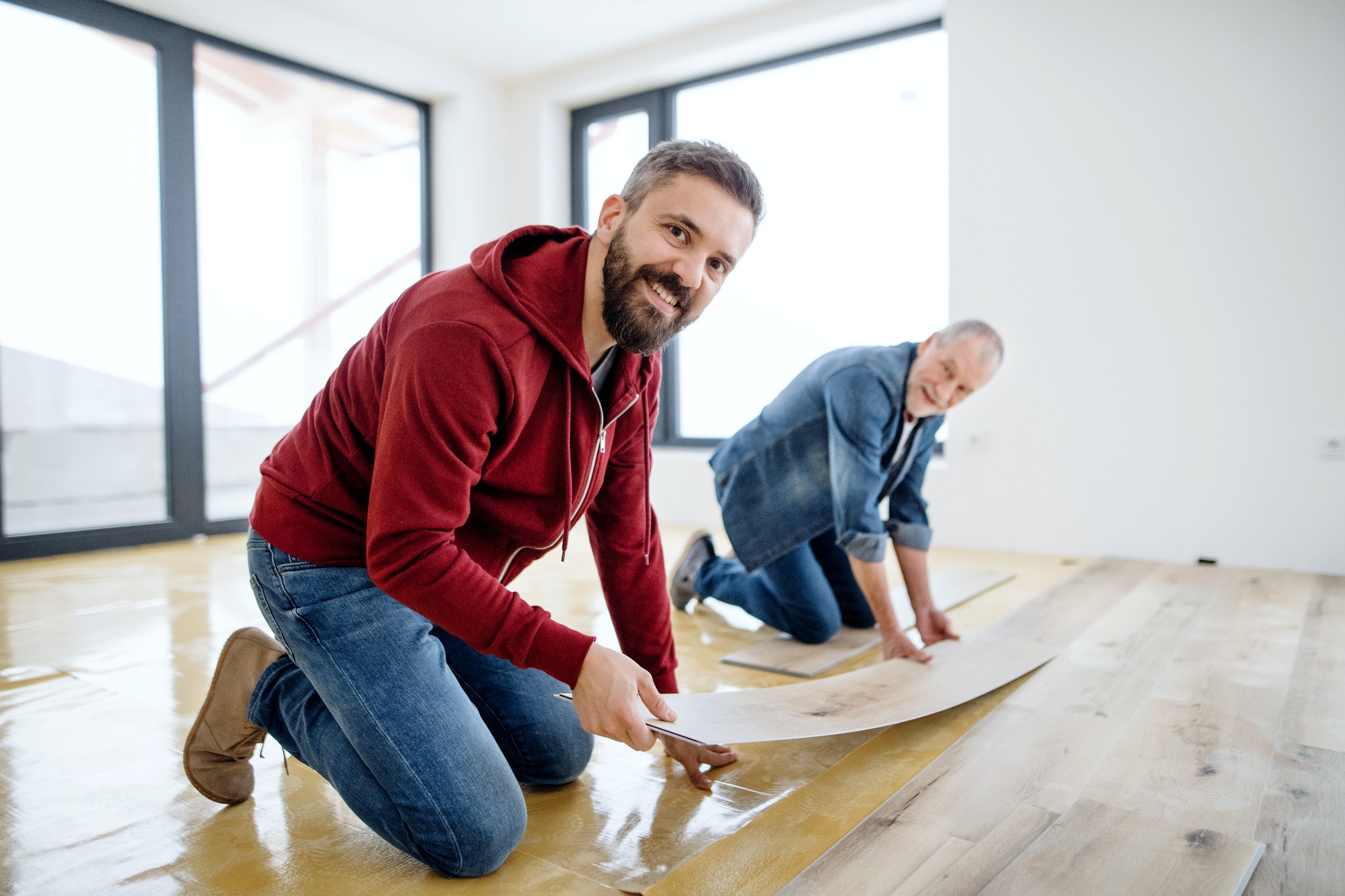 a-mature-man-with-his-senior-father-laying-vinyl-flooring-a-new-home-concept-.jpg